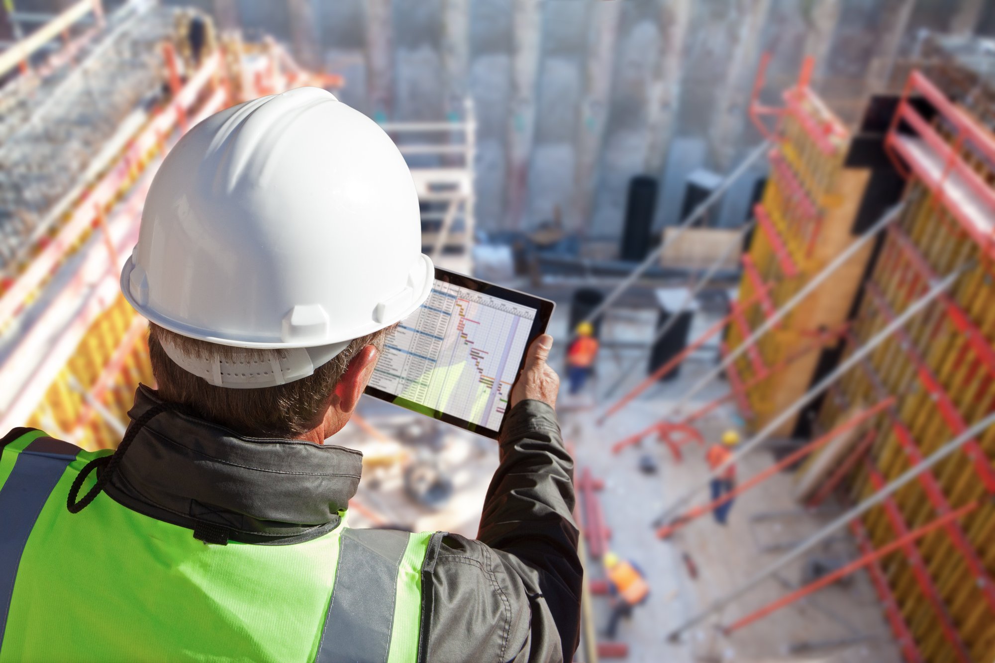 Image of a man looking at his tablet on a construction site, symbolizing GearTrack's ability to provide real-time monitoring and alerts of fleet vehicles.
